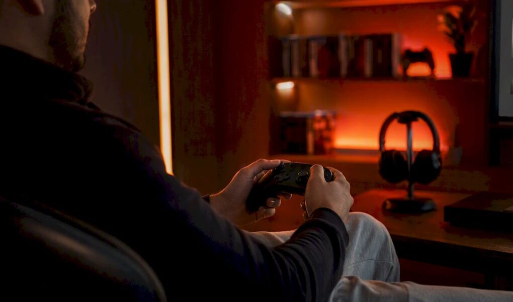 Hands holding game controller in red-lit room