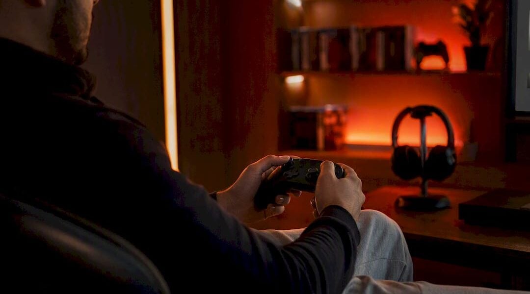Hands holding game controller in red-lit room