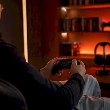 Hands holding game controller in red-lit room