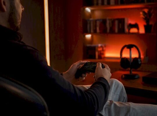 Hands holding game controller in red-lit room