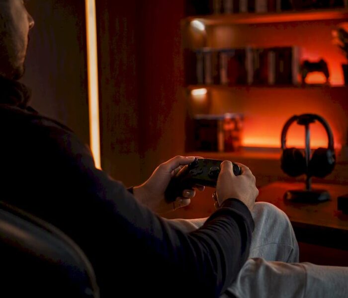 Hands holding game controller in red-lit room